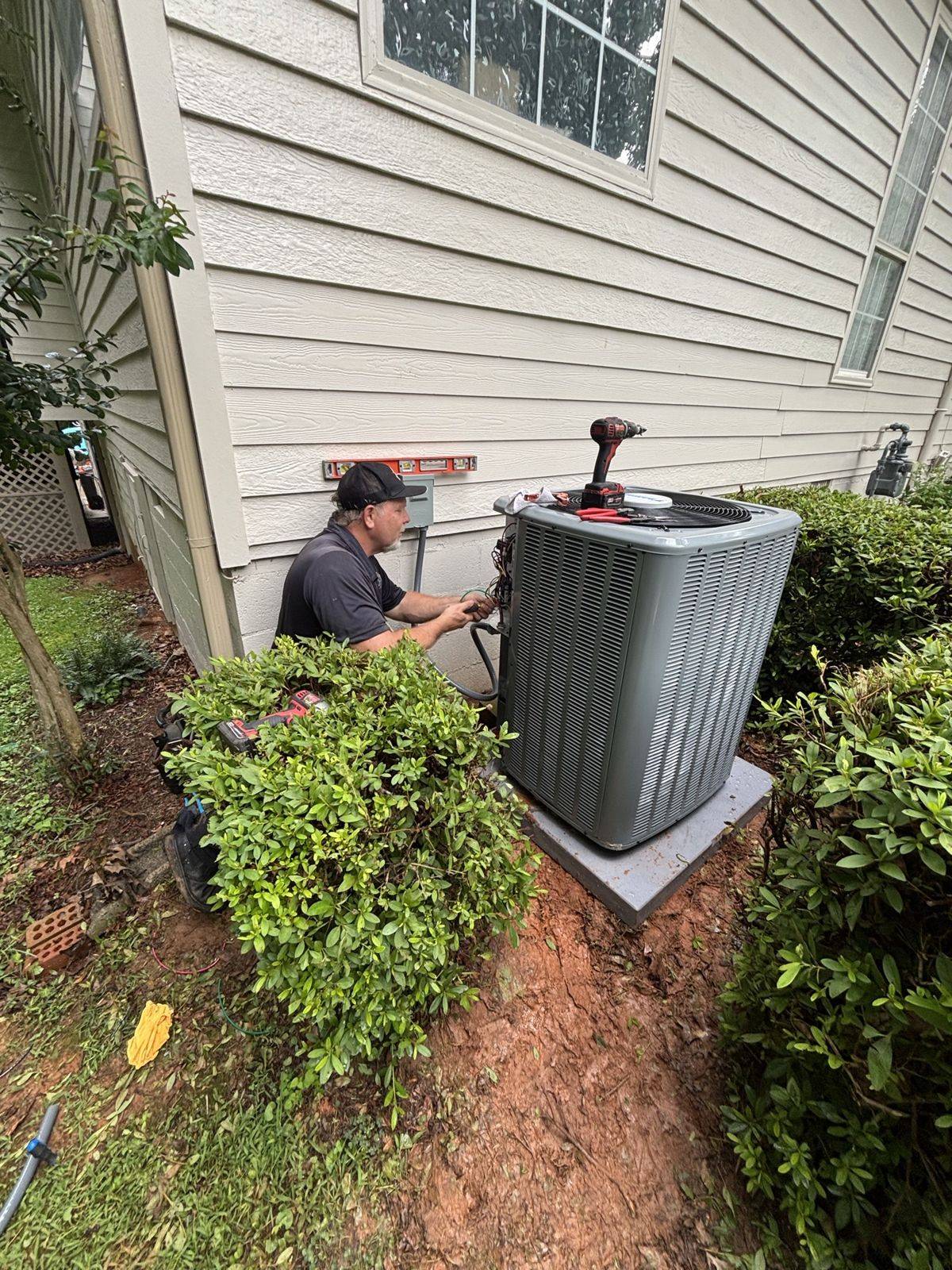 Crane setting a new condenser at a home